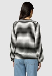 Chemise à rayures noires et blanches à manches longues avec des manches bouffantes. Confectionnée en tissu doux, elle possède un col rond et des poignets élastiqués.