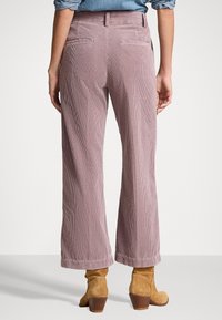 Široké kalhoty z kordu v jemně růžové barvě s decentní jemnou strukturou. Obsahují dvě zadní kapsy a ohrnuté lemy pro vylepšení detailů.