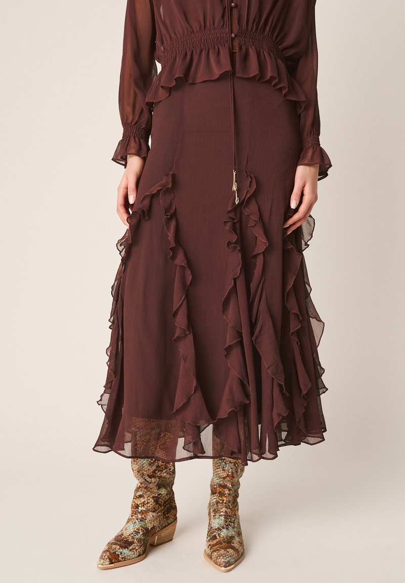 Gonna lunga marrone con strati arricciati abbinata a stivali a metà polpaccio con motivo a pelle di serpente e tacchi bassi in legno.