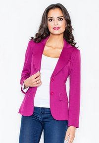 Fuksjowa marynarka z klapami, dwoma guzikami i bocznymi kieszeniami, zestawiona z białą bluzką i ciemnymi dżinsami. Gładka faktura materiału.