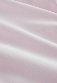 Tessuto morbido rosa chiaro con trama finemente strutturata e pieghe delicate che creano ombre e luci sottili.