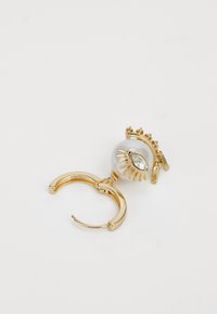 Boucle d'oreille en or avec une grande perle ronde blanche ornée d'un motif oeil décoratif et d'un accent en cristal, reliée par une petite chaîne.