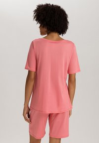 Roze katoenen loungeoutfit bestaande uit een T-shirt met korte mouwen en bijpassende shorts. De stof is zacht en glad, met een relaxte pasvorm en bescheiden halslijn.