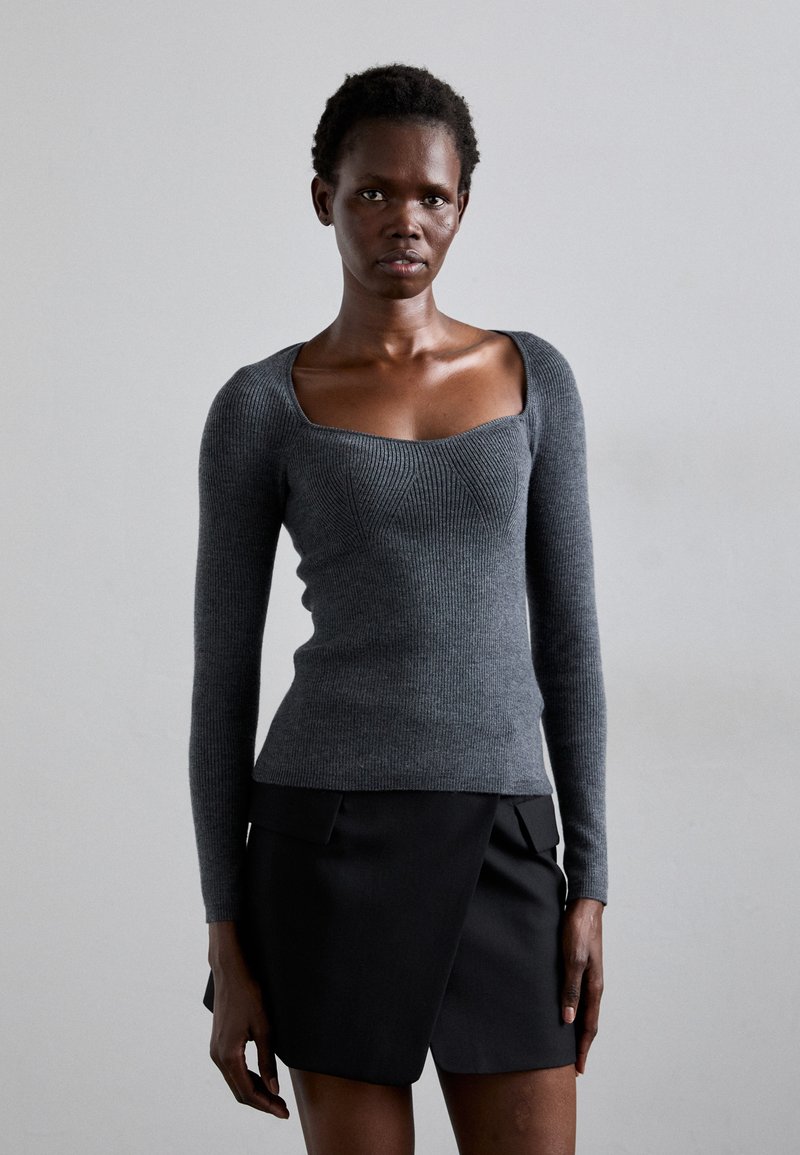 Gray ribbed knit sweater with a square neckline and long sleeves, paired with a black pleated mini skirt. Smooth texture and fitted design.