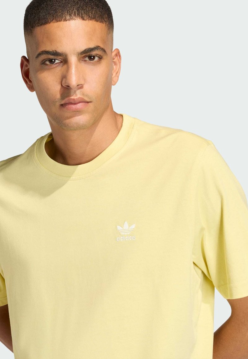 Yellow cotton t-shirt with a round neck, short sleeves, and white embroidered Adidas logo on the left chest. Smooth texture.