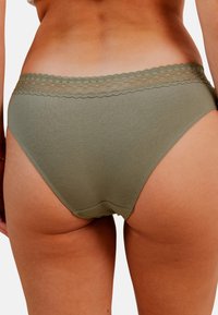 Slips en coton vert olive avec une taille en dentelle festonnée, présentant une texture lisse et une coupe classique à taille mi-haute.