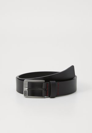 Ceinture en cuir noir avec une boucle en métal argenté et des accents de surpiqûres rouges, présentant une texture lisse et mate ainsi qu'un design classique.