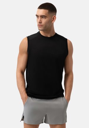 Sort ærmeløs træningsskjorte lavet af glat stof, med rund hals og minimal syning. Parret med lysegrå shorts.