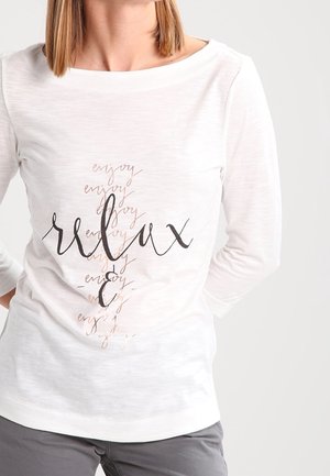 Weißes Langarmshirt mit dem Wort "relax" in schwarzer Schrift und dem Wort "enjoy" in sanftem Rosa, aus einem leichten, strukturierten Stoff gefertigt.