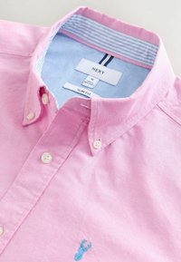 Schmal geschnittenes rosa Hemd aus Baumwolle mit einem hellblauen gestreiften Kragen und einem kleinen blauen gestickten Hummer-Detail auf der Brust. Weiße Knöpfe.