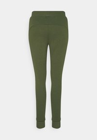 Olivegrønne leggings lavet af blødt, strækbart materiale. Har en høj talje og smalle ankler med tætsiddende manchetter.