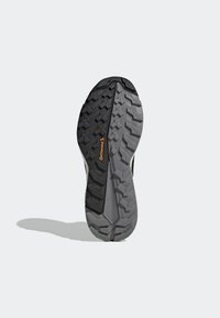 Semelle de chaussure avec un motif de bande de roulement en caoutchouc noir et gris, présentant le logo Continental près du centre sur un fond clair.