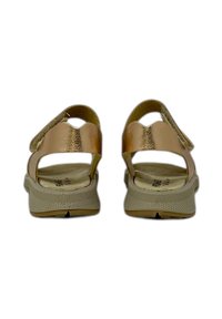 Sandali in oro rosa con due cinghie regolabili, una soletta beige imbottita e suola in gomma testurizzata per grip e supporto.
