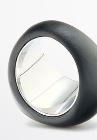 Zwarte en zilveren ring met een afgerond ontwerp, matte textuur aan de buitenkant en een gepolijste binnenkant met zichtbare lijnen.