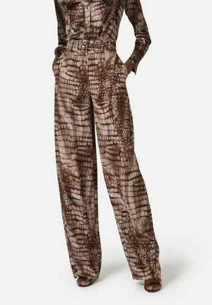 Pantaloni a vita alta e gamba larga con stampa rettile marrone, indossati con top a maniche lunghe abbinato e sandali con punta aperta.