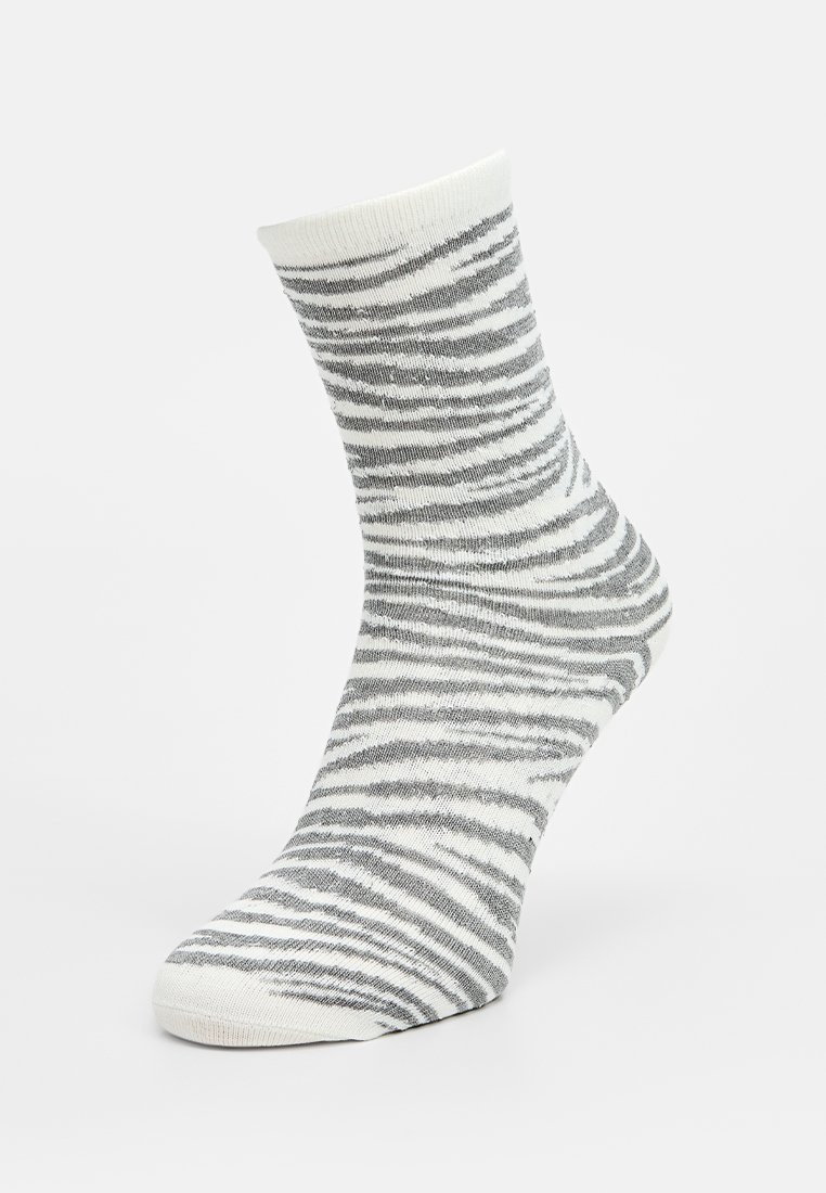 Calcetín a rayas gris y blanco con puño acanalado, hecho de tela suave, que presenta un diseño texturizado que imita las rayas de animales.