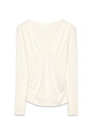 Long-sleeve top in cream, featuring a deep V-neck, gathered detailing at the bodice and sleeves, and a soft, stretchy fabric.
