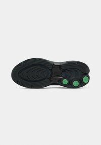 Semelle de chaussure noire avec grip texturé, trois inserts circulaires verts avec les lettres "V", "D" et "S", et un logo embossé au centre.