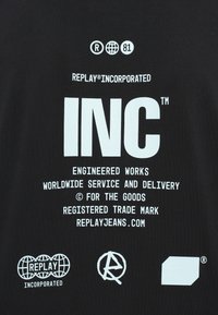 Λευκό κείμενο και λογότυπα σε μαύρο φόντο που περιλαμβάνουν τις λέξεις "INC", "Replay Incorporated" και την ιστοσελίδα "replayjeans.com" με σύμβολα κατοχυρωμένου εμπορικού σήματος.