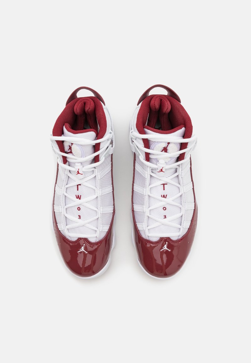 Baskets de sport rouges et blanches avec un dessus en cuir verni et en mesh, bout rond, système de laçage et logo bien visible sur les côtés.