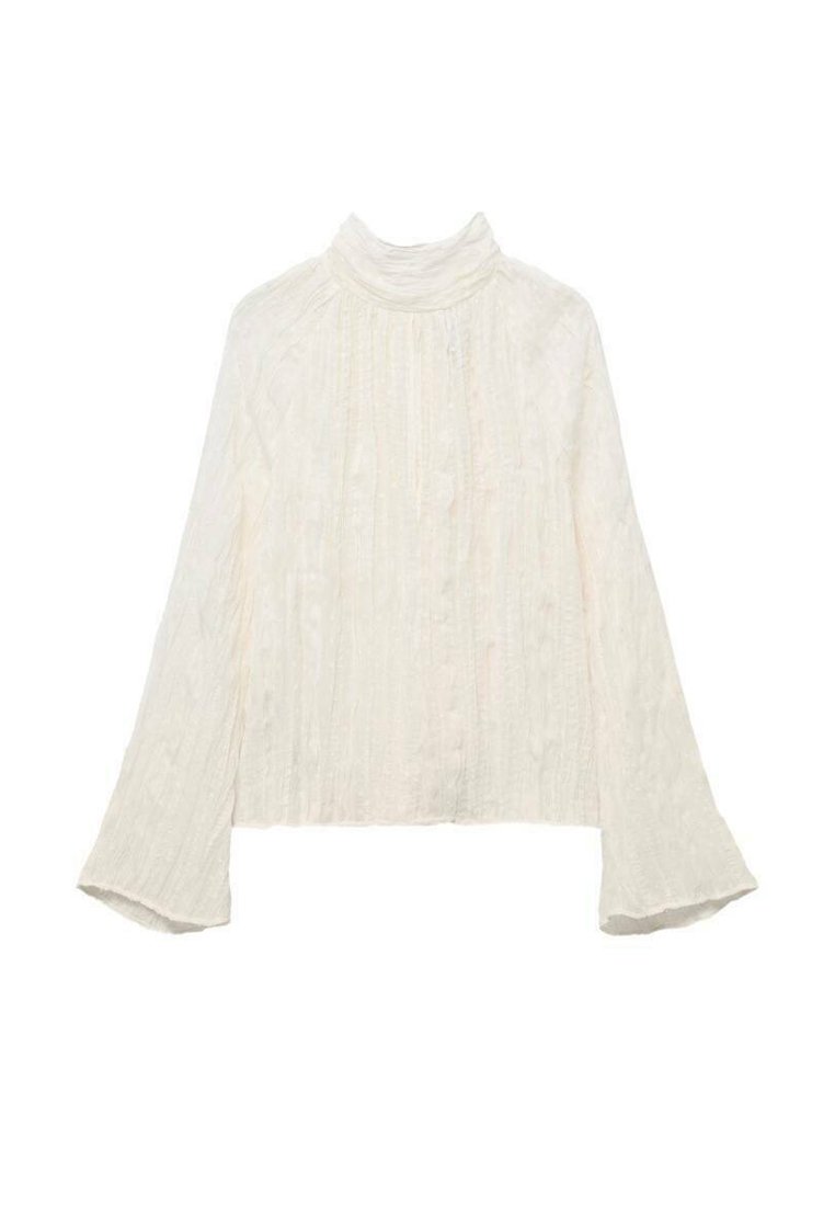 Blusa blanca de manga larga con un cuello alto, que presenta un patrón texturizado y puños acampanados. El material parece ligero y ligeramente transparente.
