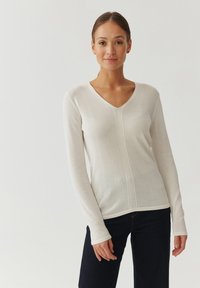 Lyscreme langærmet sweater med V-hals, der har et struktureret stof og sømdetaljer, der løber lodret ned langs fronten og bagsiden.