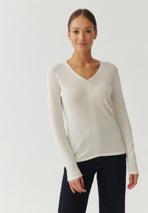 Maglione a maniche lunghe color crema chiaro con scollo a V, caratterizzato da un tessuto strutturato e dettagli di cucitura che si estendono verticalmente sulla parte anteriore e posteriore.