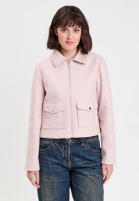 Giacca corta rosa con colletto, zip frontale e due tasche sul petto. Il tessuto ha una consistenza morbida, con maniche lunghe e linee pulite.