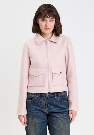 Roze korte jas met kraag, ritssluiting aan de voorkant en twee borstzakken. De stof heeft een zachte textuur, met lange mouwen en strakke lijnen.