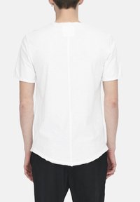 Weißes kurzärmliges T-Shirt mit Rundhalsausschnitt, aus weichem Baumwollmaterial, und einer mittleren vertikalen Naht auf der Rückseite, mit abgerundetem Saum.