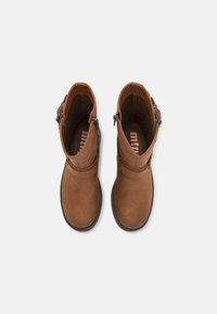 Botas de tobillo de ante marrón con una textura suave, cremalleras a los lados y un diseño de punta redondeada. El interior cuenta con una plantilla con la marca.