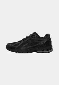 Baskets de sport noires avec une tige en mesh ornée d'accents texturés, semelle en caoutchouc et système de laçage, conçues pour le confort et le soutien.