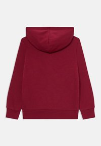 Bordeaux huppari, jossa on pehmeä tekstuuri, suuri huppu ja pitkät hihat. Sisältää ribbireunat hihansuissa ja helmassa, sileä pinta ilman kuvioita.