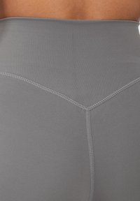 Leggings grigi alti in vita realizzati in tessuto elasticizzato, caratterizzati da un design elegante con una texture liscia e dettagli di cucitura a contrasto.