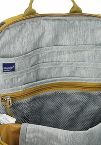 Binnenkant van een rugzak met grijze stofvoering, meerdere georganiseerde vakken, een geperforeerd ritscompartiment en een "bluesign product" label.