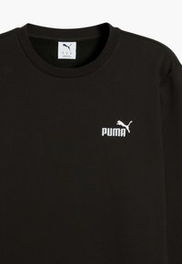 T-shirt in cotone nero con scollatura tonda, maniche corte e logo Puma bianco sul lato sinistro del petto. Texture morbida, design minimalista.