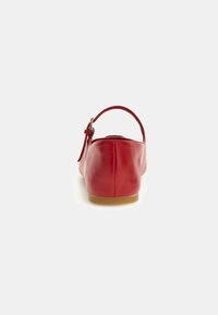 Rood leren ballerina schoen met een ronde neus en een enkele verstelbare band, met een platte, lichtgekleurde zool.