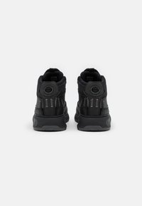 Sneaker alte nere con tomaia in pelle liscia, suola ammortizzata e dettagli cuciti. Dettagli riflettenti vicino alla caviglia.