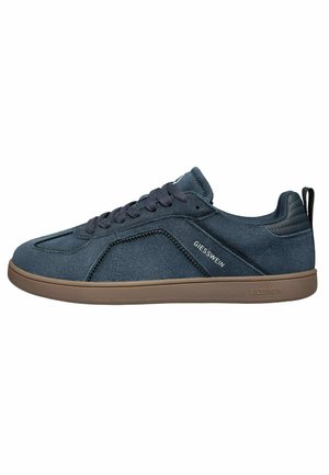 Męski ciemnoniebieski zamszowy sneaker z brązową podeszwą, zapinany na sznurowadła, z logo "Giesswein" po boku i na podeszwie oraz z wyściełanym kołnierzem na pięcie.