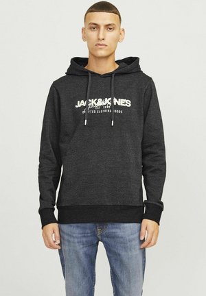 Grauer Hoodie mit einem großen weißen Logo und Text auf der Vorderseite, mit Zugbändern und einer Kängurutasche. Kombiniert mit blauen Jeans.