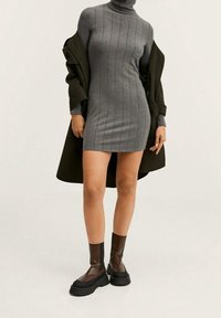 Szara sukienka z ribbowanym golfem o dopasowanym kroju. W połączeniu z ciemnozielonym płaszczem i brązowymi masywnymi botkami za kostkę.