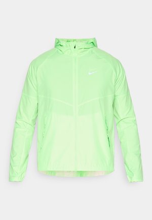 Veste Nike vert clair avec zip sur le devant, capuche, manches longues et poches latérales. Texture lisse et logo réfléchissant sur la poitrine.
