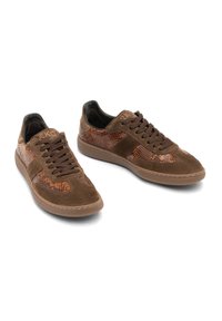 Brązowe sneakersy wykonane z zamszu i teksturowanej skóry z wzorem w węża. Posiadają okrągły czubek, sznurowane zapięcie oraz gumową podeszwę.