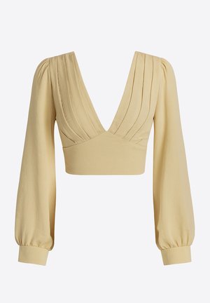 Haut court jaune avec un décolleté en V profond, détails plissés au niveau de la poitrine et manches longues bouffantes. Confectionné dans un matériau à texture lisse.