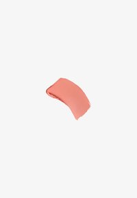 Tache de maquillage crème mat couleur corail avec une texture lisse sur un fond blanc uni.
