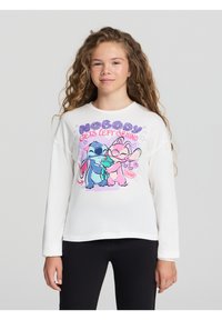 Biała koszulka z długim rękawem z kolorowym nadrukiem z kreskówkowymi postaciami w odcieniach niebieskiego i różowego oraz napisem "NIKT NIE ZOSTAJE ZAAWAŻONY."