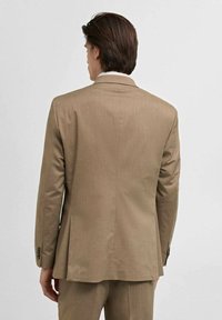 Giacca su misura marrone con un design pulito, caratterizzata da una tasca singola, vestibilità slim e una trama sottile nel tessuto.