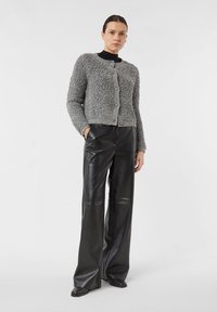 Szary, puszysty kardigan z zapięciem na guziki, zestawiony z czarnymi skórzanymi spodniami o szerokich nogawkach. Prosta konstrukcja, bez widocznych wzorów.