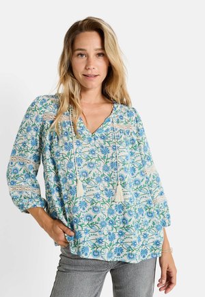 Blusa con estampado floral en azul claro y blanco, con escote en V, cintilla con borlas y detalles de encaje en las mangas. Tejido texturizado.