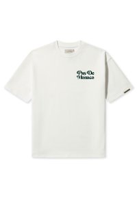 Camiseta de algodón blanca con mangas cortas y cuello redondo. Presenta un diseño de texto verde "Pas De Monaco" en el área del lado izquierdo del pecho.